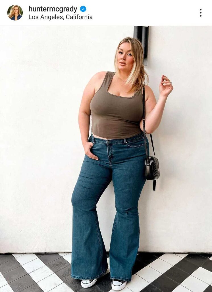 A photo of Hunter McGrady pulled from her instagram, of her in her "All Worthy" QVC collection pieces. She is wearing a brown tank top and blue jeans