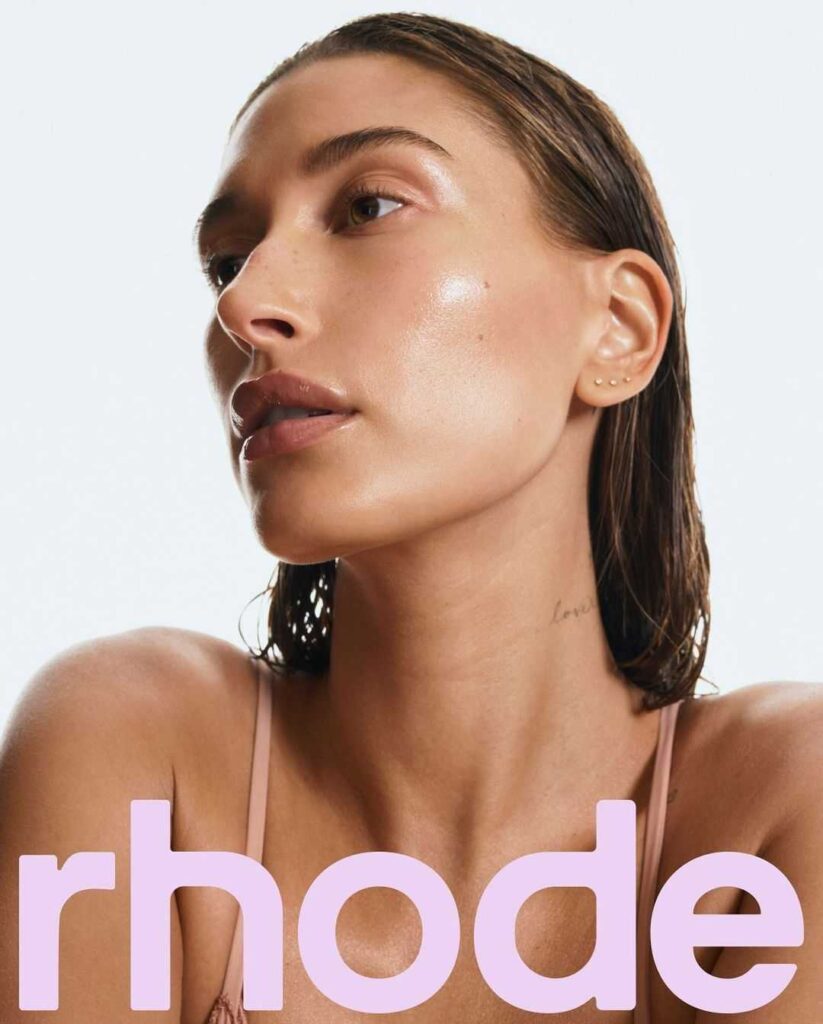 A promotional photo of Hailey Bieber with rhode written over the bottom of it- from her new skincare line Rhode Skin
