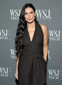 A photo of Demi Moore infront of a WSJ Tech step and repeat - In the photo her dark hair is hip length