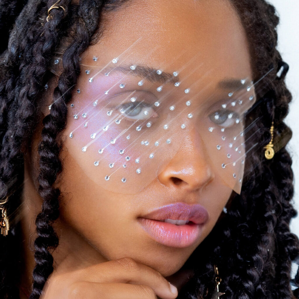 A promotional photo from Bakeup Beauty of a model wearing The Disco Veiler, a gem laced eye mask